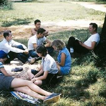 Clarence Jordan and others sitting on the ground under a tree studying