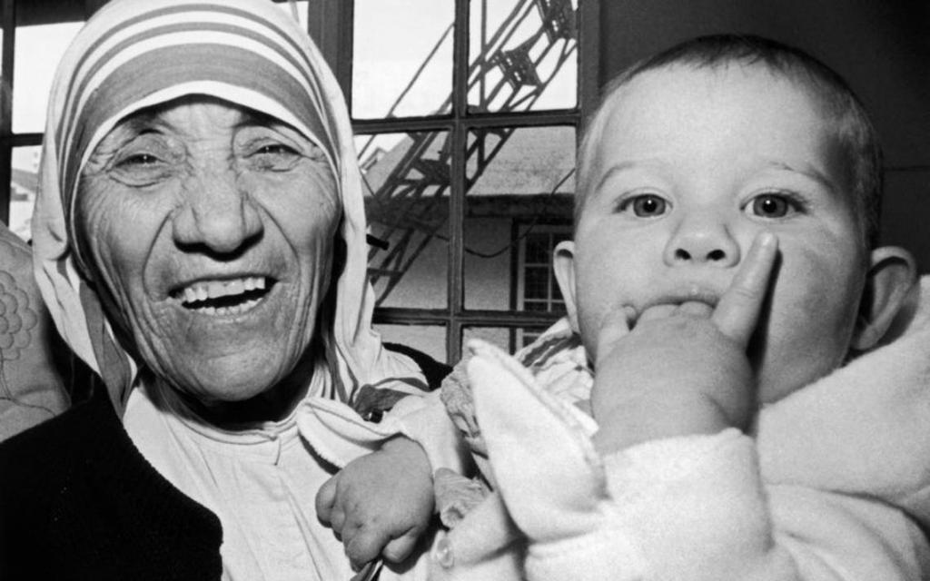 Mother Teresa laughing holding a baby